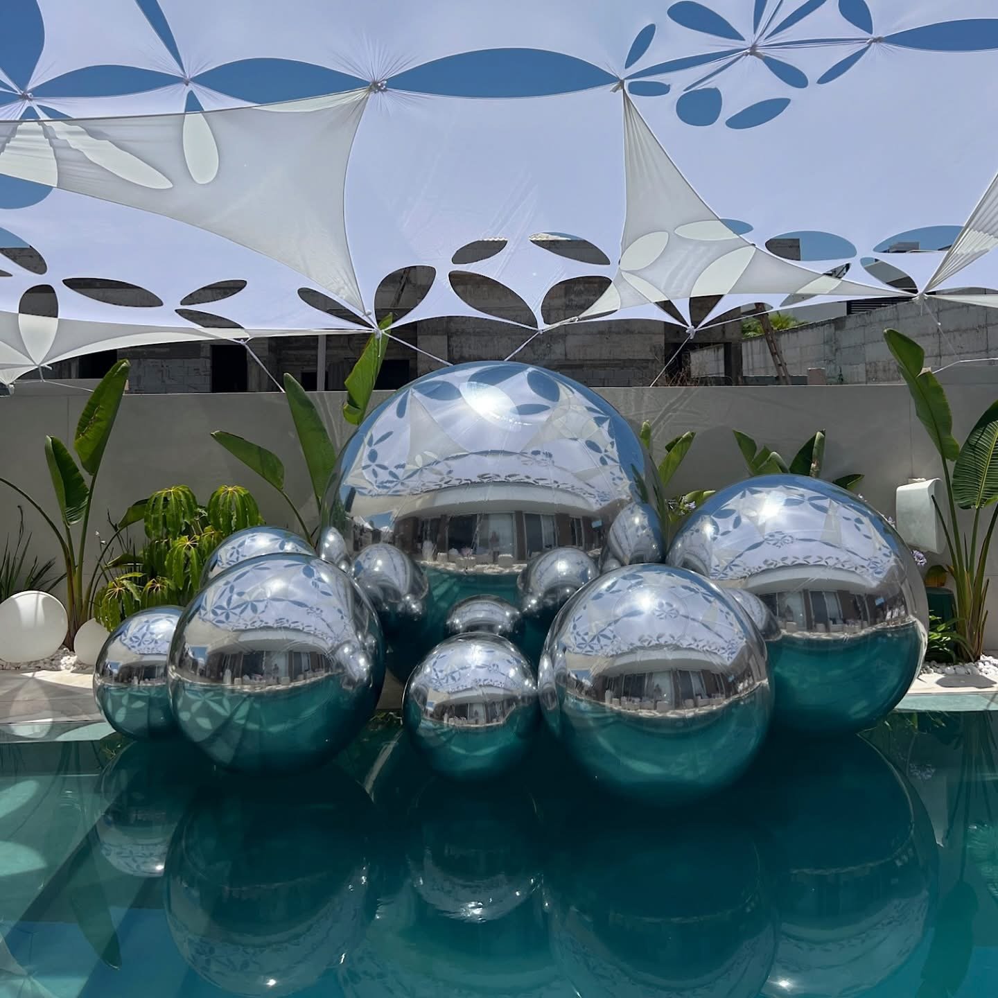 Ballons miroirs argentés de plusieurs diamètres dans un décor de piscine