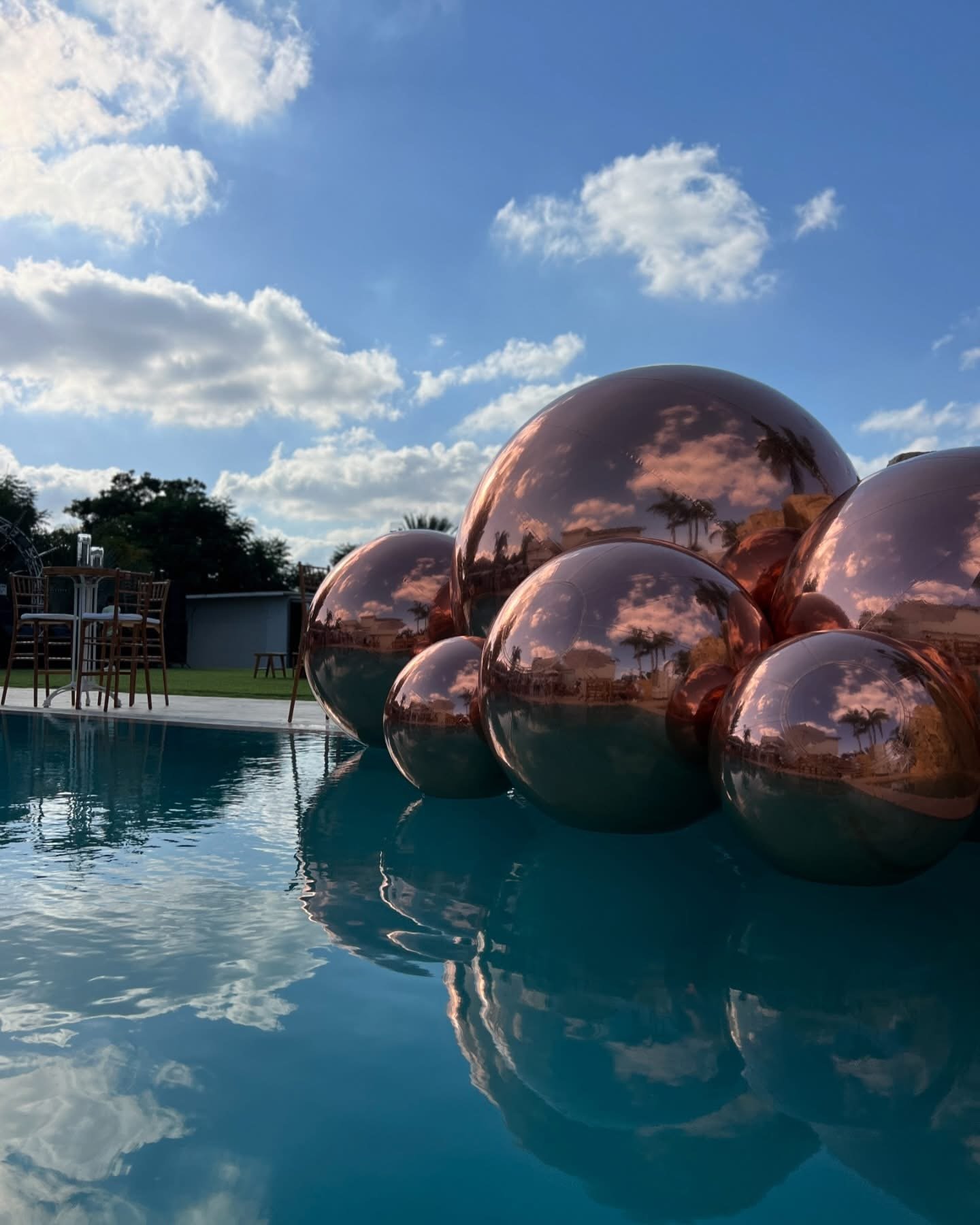 Composition de ballons miroirs cuivrés se reflétant dans une piscine