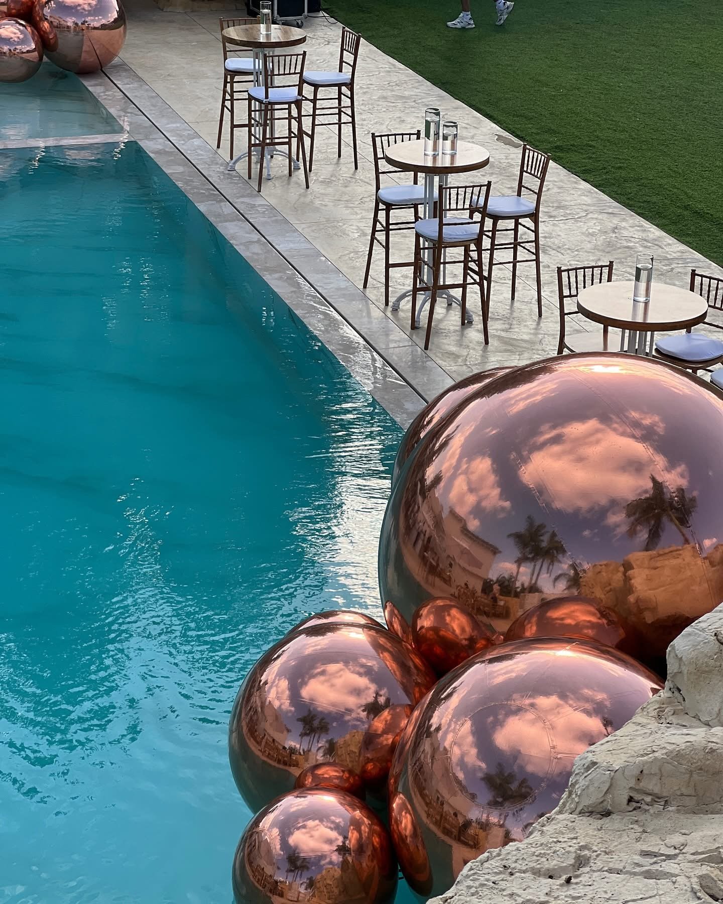 Ballons miroirs cuivrés au bord d’une piscine, vue en hauteur