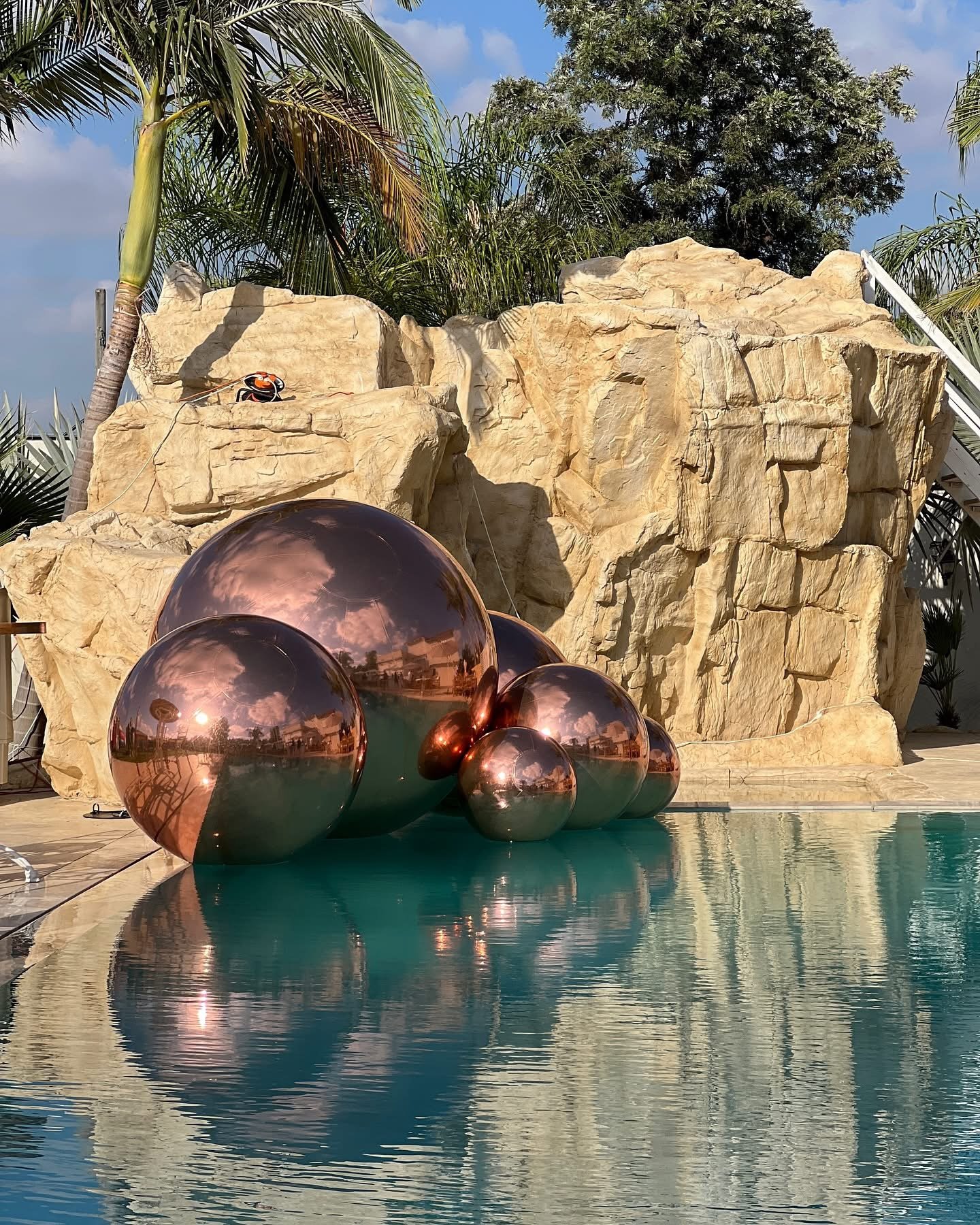 Ballons miroirs aux reflets cuivrés dans un décor extérieur avec palmiers