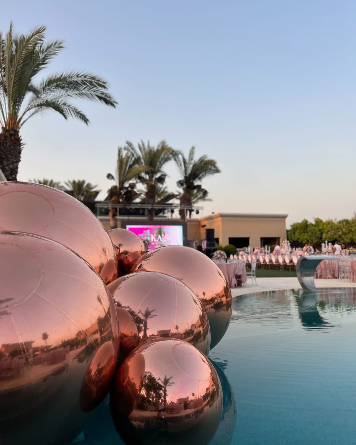 Ballons miroirs aux reflets rose doré dans un espace de réception extérieur