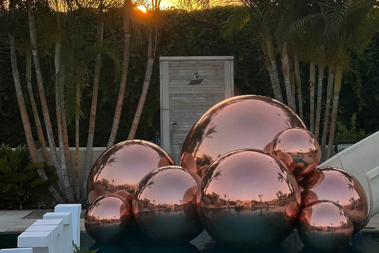 Ballons miroirs aux reflets cuivrés dans un jardin à la tombée du jour