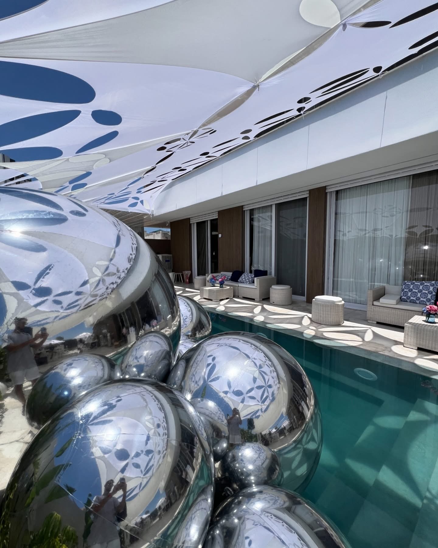 Détail de ballons miroirs argentés dans un espace avec piscine