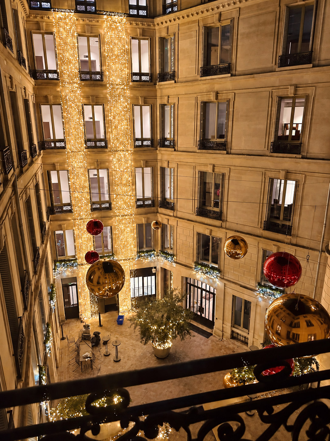 Vue en hauteur de ballons miroirs rouges et dorés dans une cour éclairée