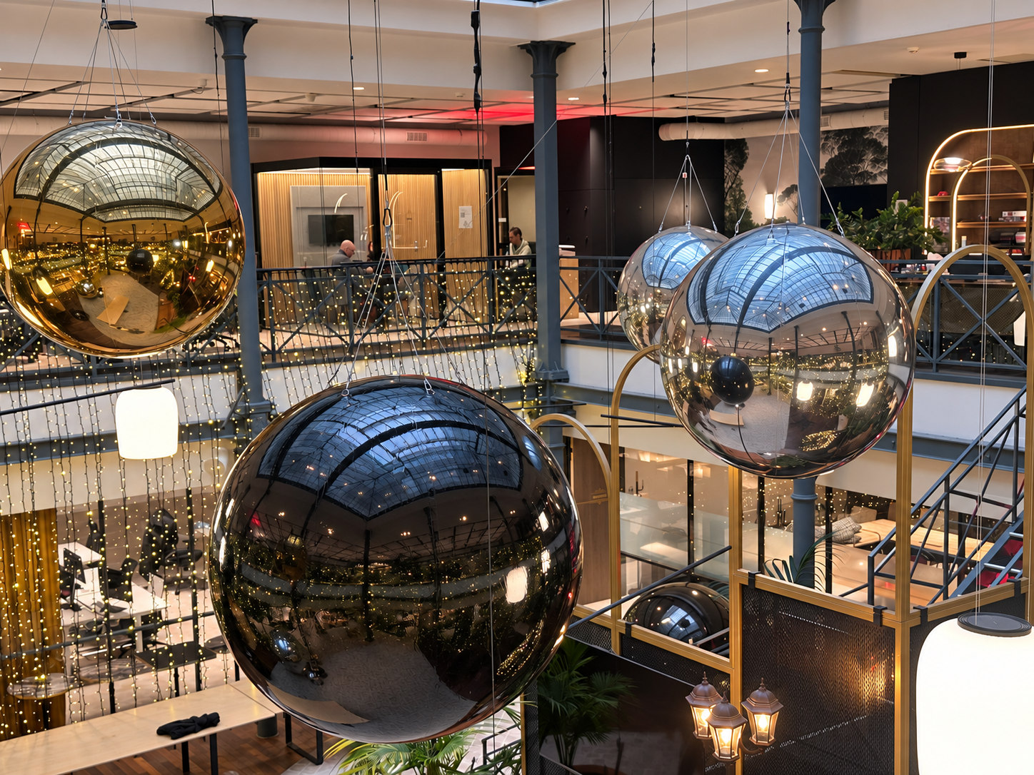 Gros plan sur des ballons miroirs dorés, argentés et noirs suspendus