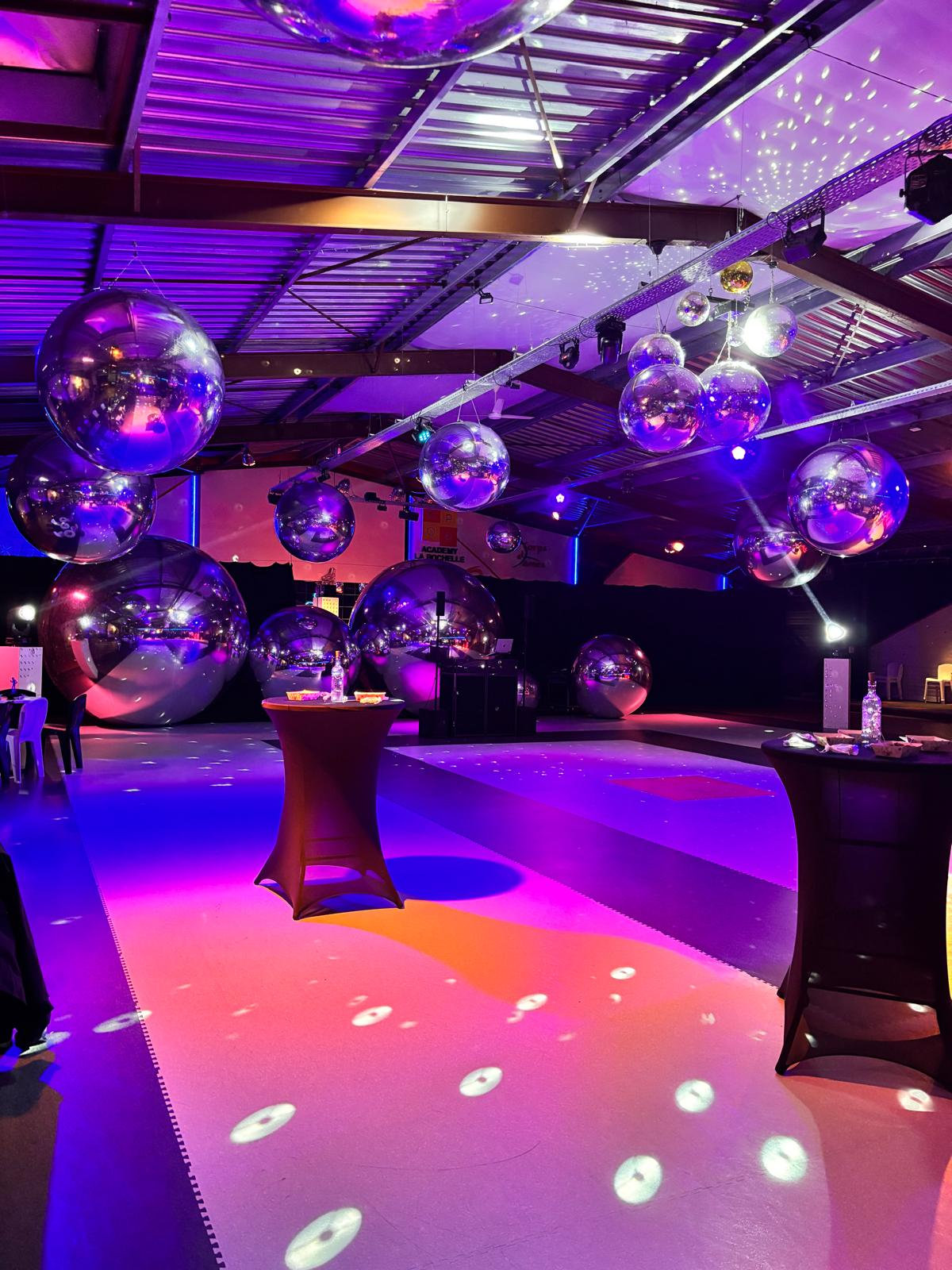 Ballons miroirs argentés dans une salle aux éclairages violets