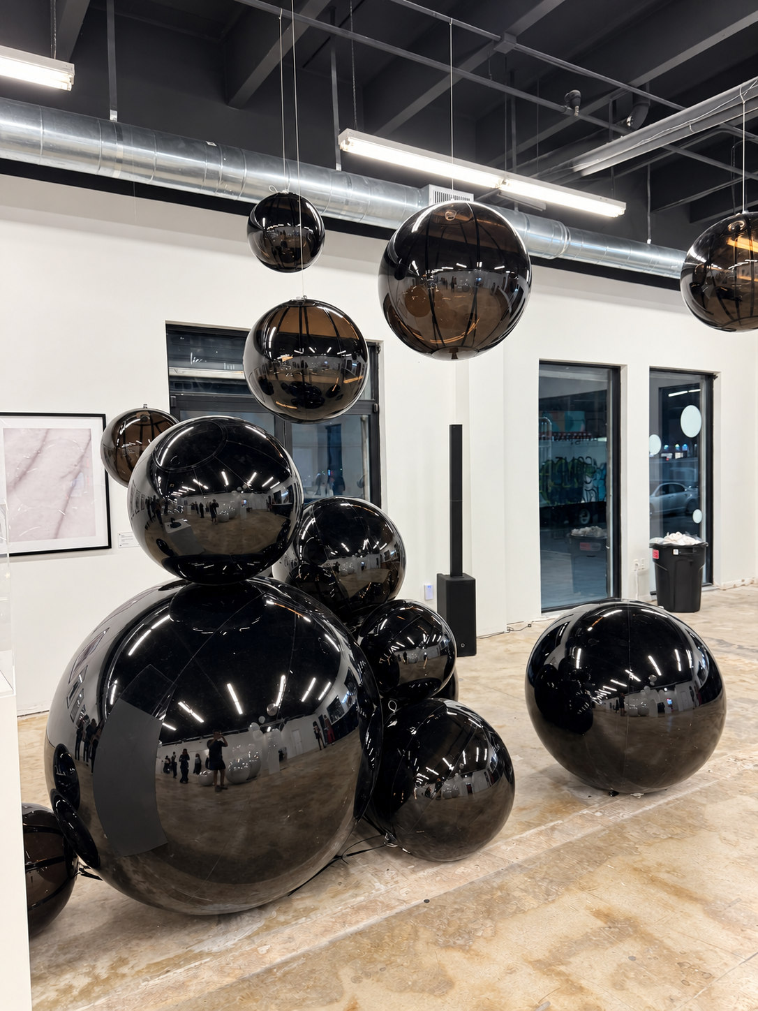 Ballons miroirs noirs, suspendus et posés au sol dans un espace intérieur