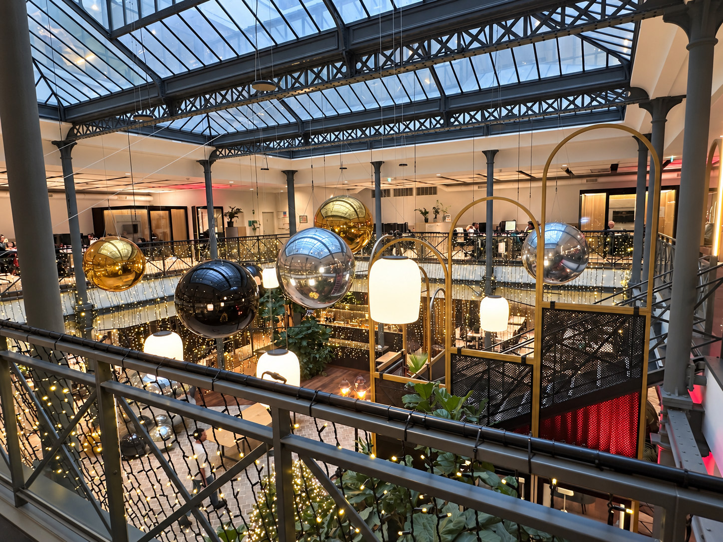 Ballons miroirs dorés, argentés et noirs sous une verrière