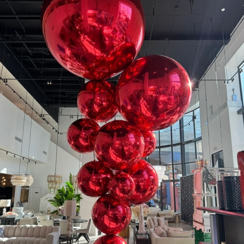Colonne de ballons miroirs rouges suspendue dans une salle