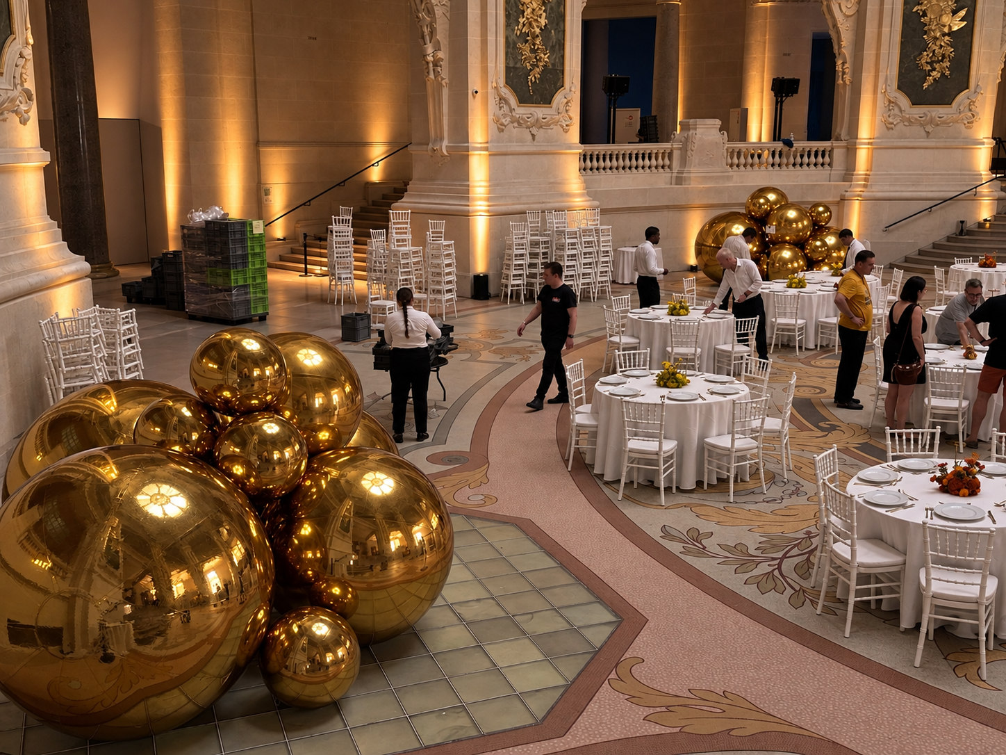 Ballons miroirs dorés au premier plan d’une réception aux lumières ambrées